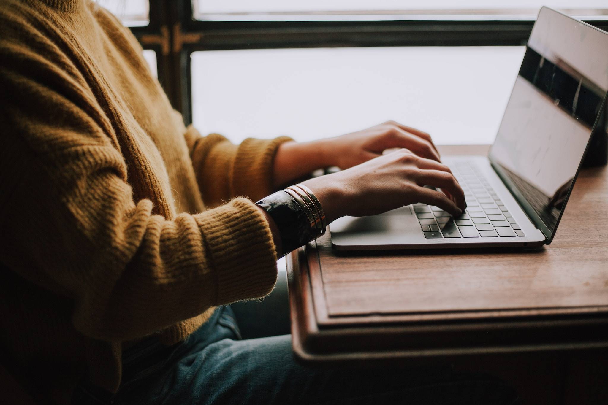 A person sitting and typing on a laptop keyboard